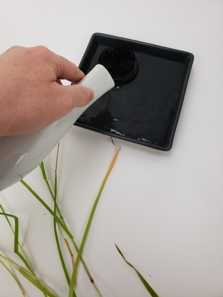 Pour water into the shallow container and make sure the Kenzan is submerged deep enough to keep the flower stems hydrated