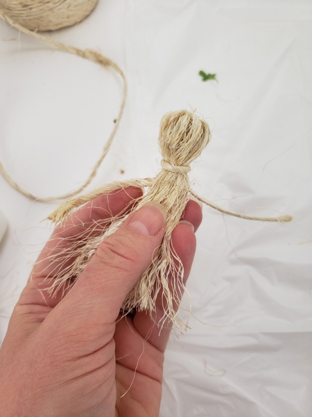 Gather the fluffed out sisal in the middle and extend the two rope pieces to the side