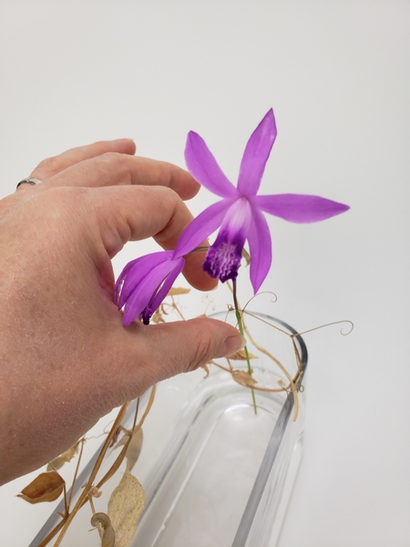 Slip the flower stem through the tendril hook and rest the stem securely on the bottom of the container