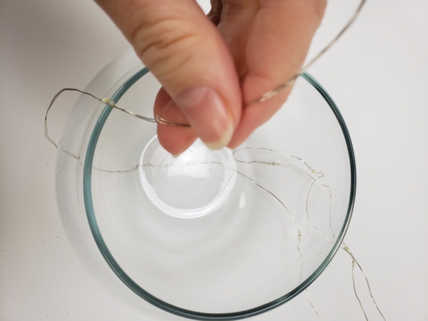 Stand the fishbowl vase on the fairy light wire