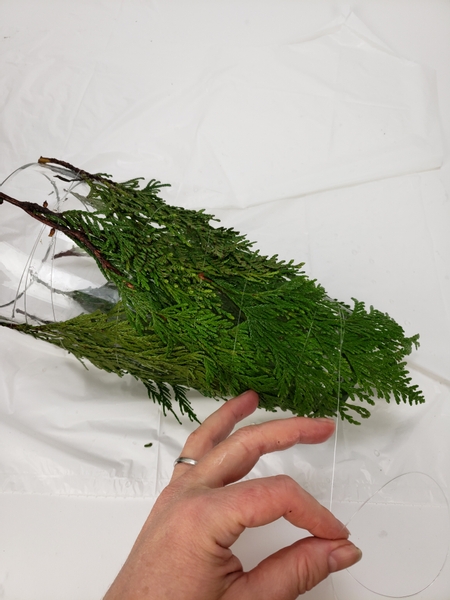 Work your way up to the tapered bottom of the vase and bind the greenery to sit tightly next to the glass