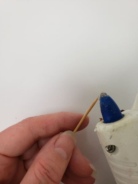 Hold a bamboo skewer under your hot glue gun to catch a drop of glue