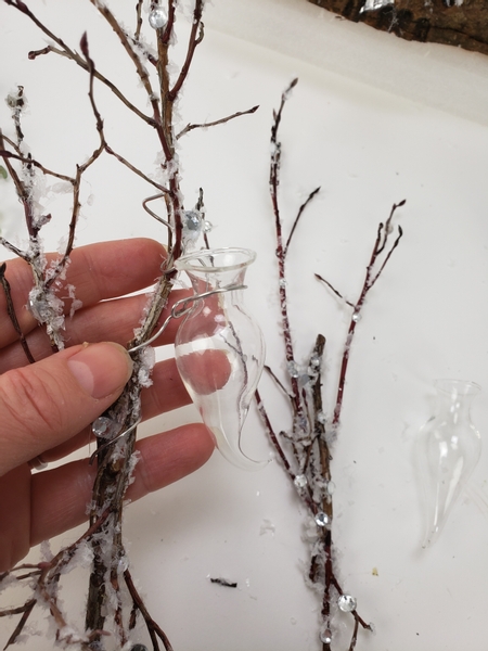 Wire a tiny glass vase or water tube into the winter twig bundle