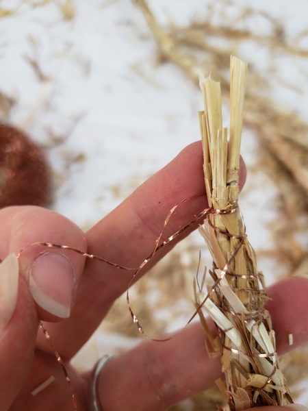 Wrap the wire around the straw garland and knot it in on itself to secure