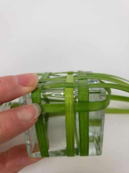 Fold the blade of grass over the bottom and start to weave it in on the side