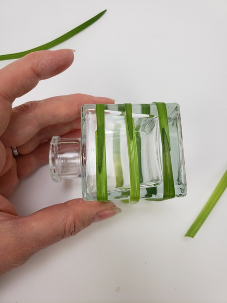 Simply wrap the blade of grass tightly around the container and secure it with a small drop of floral glue