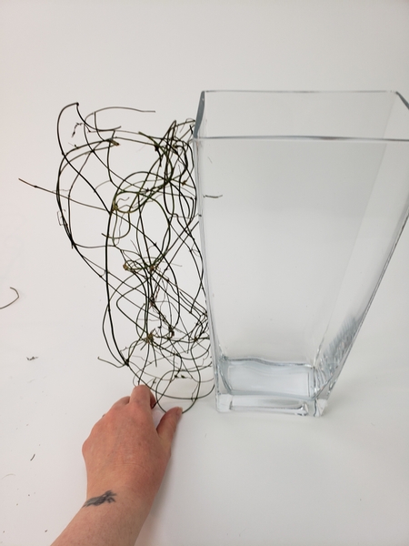 Use hot glue to glue the vine tangle to the glass container