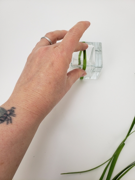 Wrap a blade of grass around the container and secure it with floral glue