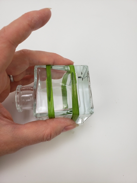 Wrap a second blade of grass around the container and secure it with glue