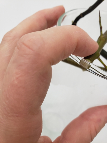 Push the twig down so that it kicks against the sides of the bud vase