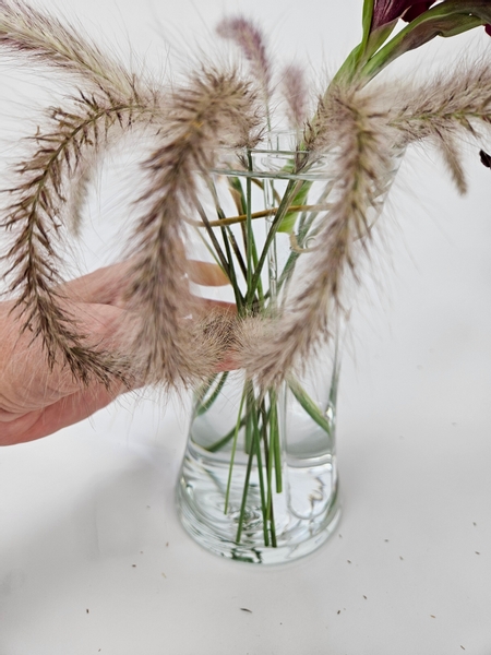 Gather three fountain grasses together and secure it to the grass line with floral glue