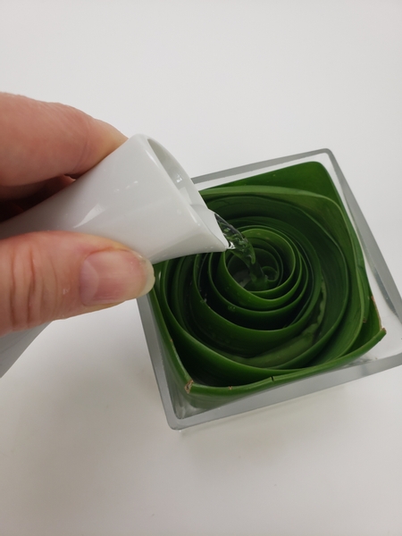 Pour water around the leaf swirl to fill the vase