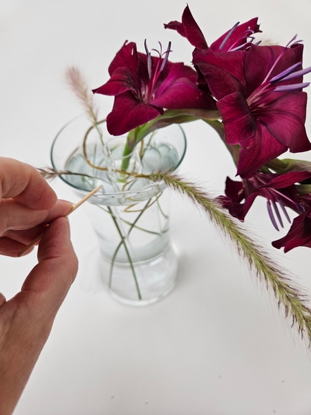 To keep the grasses from moving secure them to the display container with the tiniest bit of floral glue