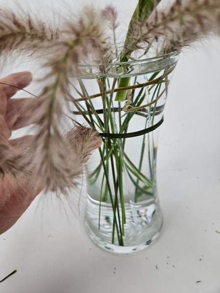 Wiggle it ever so slightly so that some of the glue also attaches the grass to the container