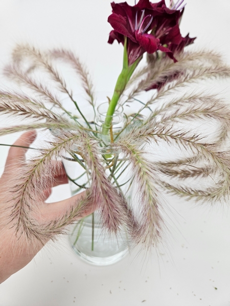 Work all the way around and secure the fountain grass in groups of three to the grass and the display container