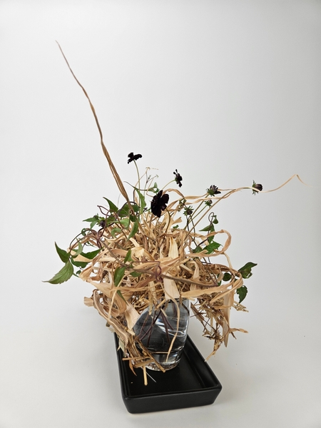 Covering a grid with straw to craft a natural floral arrangement without using floral foam