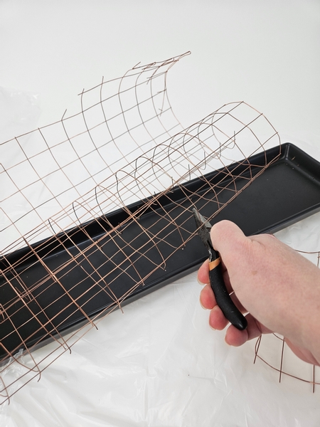 Measure out wire mesh so that a roll comfortably fits in a display tray