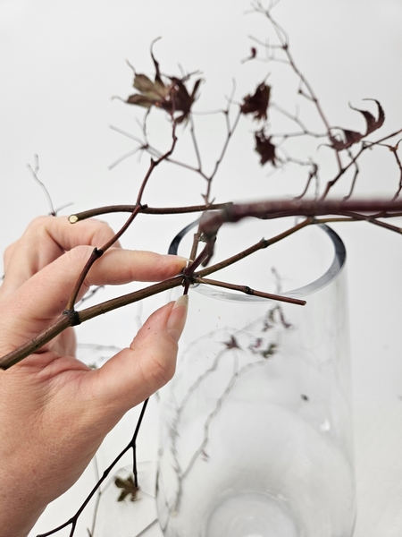 Add in more stems to shape a wave above the glass container