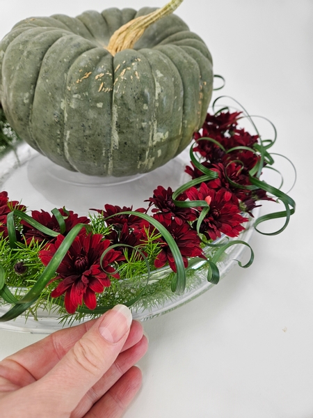 Pay special attention to curve the grass curls over the front edge of the container so that blend the glass edge of the design with the flower filled top