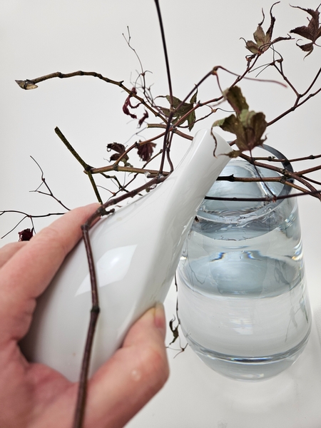 Pour water into the container to right up to just below where the dried twigs are positioned over the vase