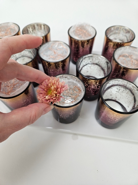 Slip the flowers into the containers so that the stems are supported by the wire mesh