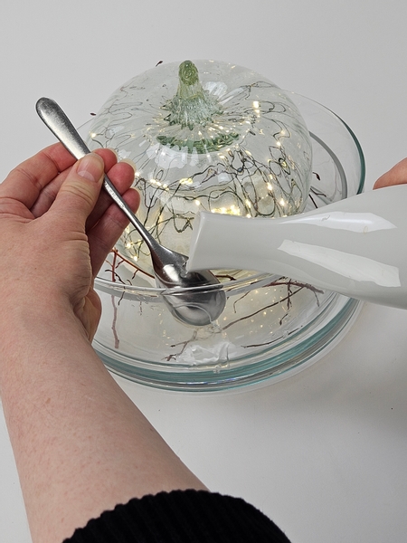 Tilt the spoon away from the edge and pour water over the spoon into the small gap