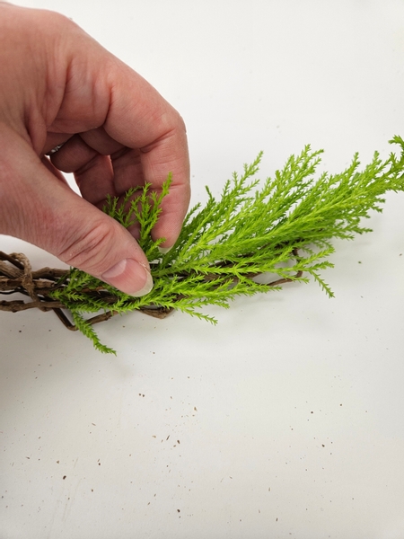 Use floral glue to secure a branch of evergreen to the twig wreath