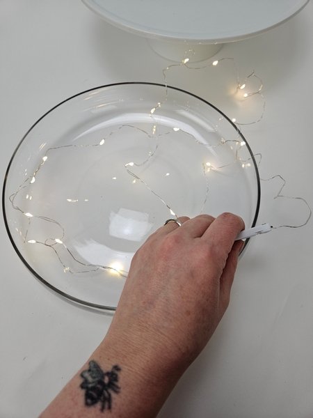 Fill the low glass container with fairy lights