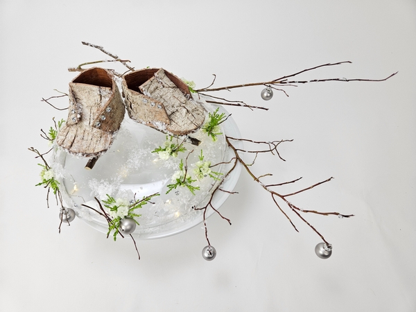 Floral design with tiny bark ice skates for a winter wonderland arrangement