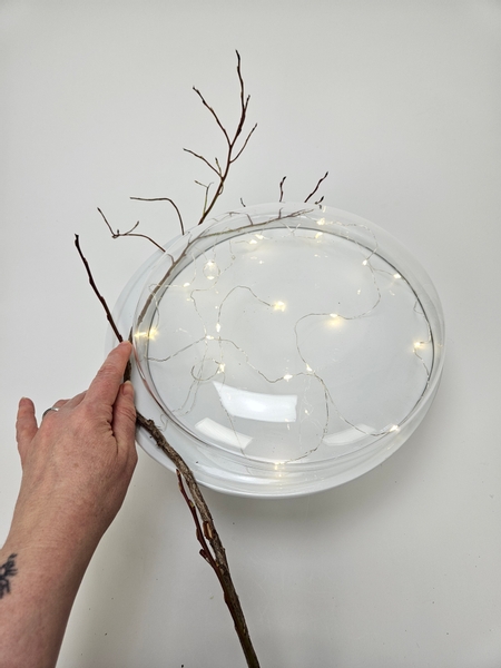 Start the design by placing a few huckleberry branches to frame the clear container