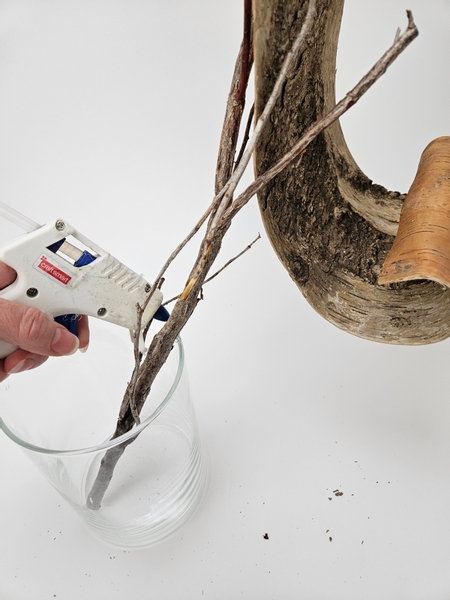 Use a glue gun to secure the twig to the vase to stop it from rolling about as you design