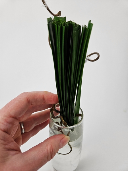 And tuck the cut end of the hazel twig into the display vase so that it wedges the entire palm lead stack into place.