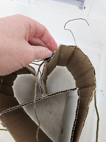 Secure a really flexible willow stem with a clip to the side of the card board heart.