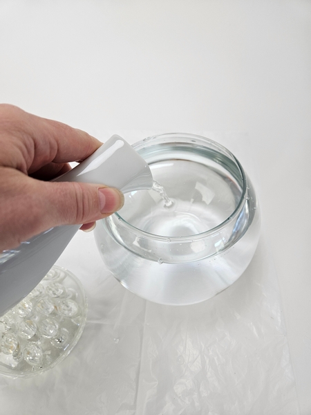 Pour water into a round fish bowl vase Pour water into a round fish bowl vase